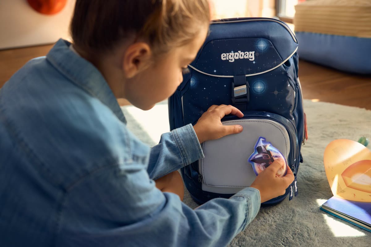 Kind klebt ein Klettie auf die Vorderseite seines Ergobag Schulranzens