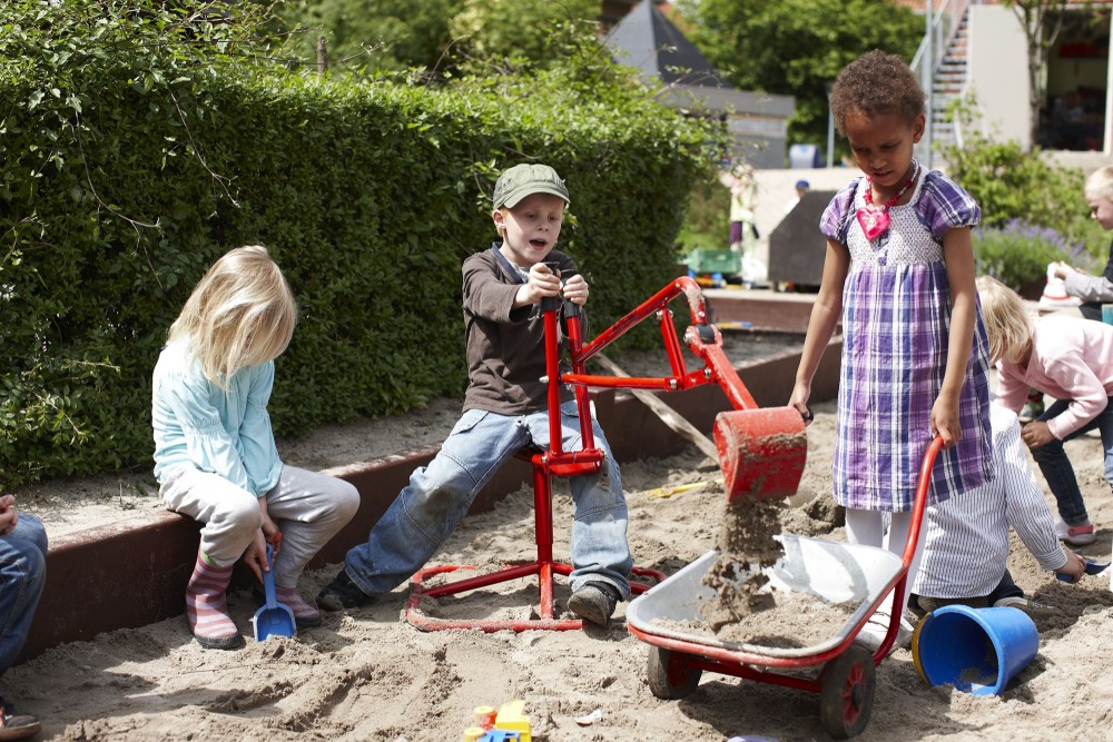 Kinder füllen mit dem Winther Viking Challenge Bagger Sand in eine Schubkarre