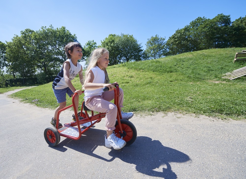 Kinder fahren das Winther Viking Dreirad Ben Hur unter blauem Himmel