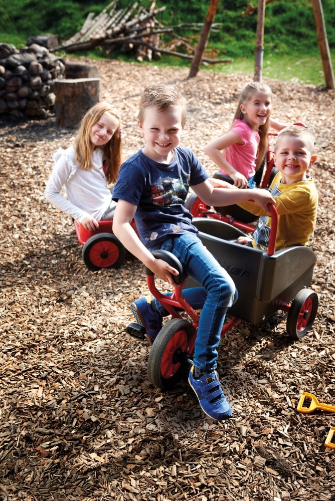 Kinder sitzen im Winther Viking Dreirad Kangaroo auf dem Spielplatz