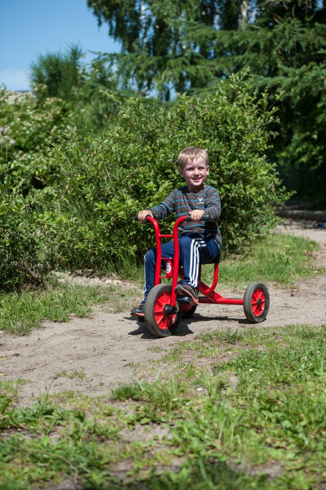 Kind fährt das Winther Viking Dreirad mittel auf einem Waldweg