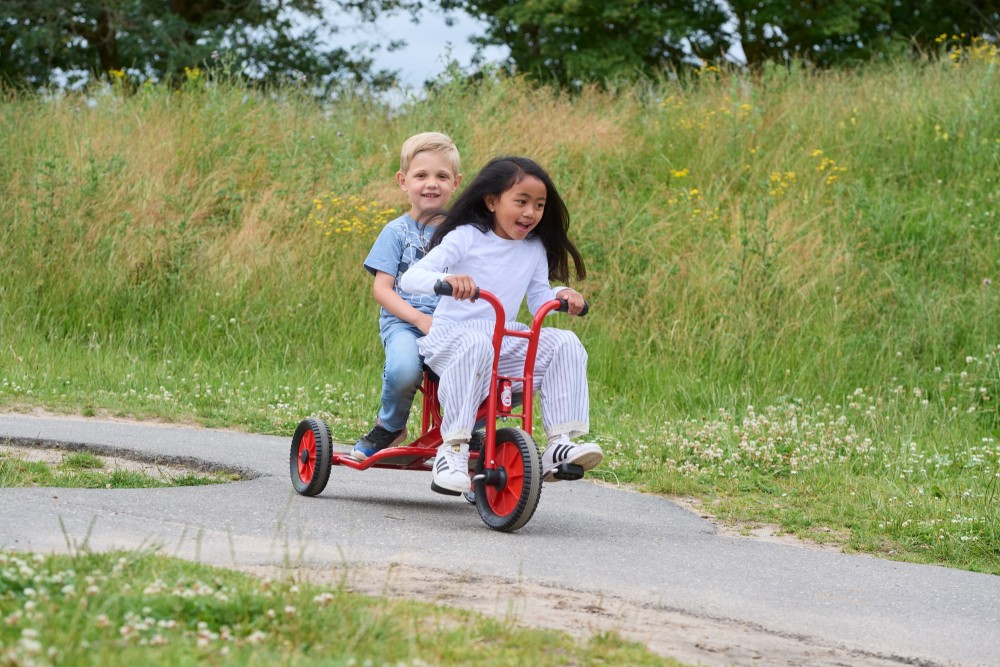 Kinder fahren mit dem Winther Viking Dreirad Taxi einen Weg entlang