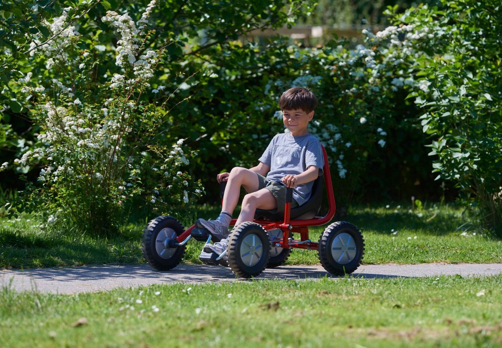 Junge fährt den Winther Viking Explorer Fun Cart Large vor einer Hecke