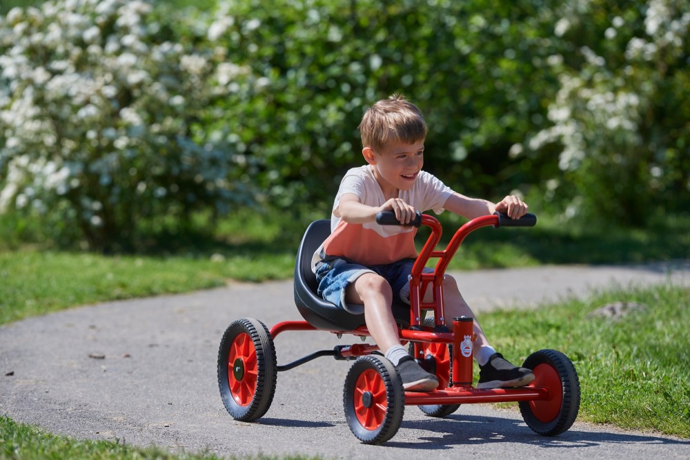 Junge im Sitz des Winther Viking Holländer Tretfahrzeug, Ansicht schräg von vorn