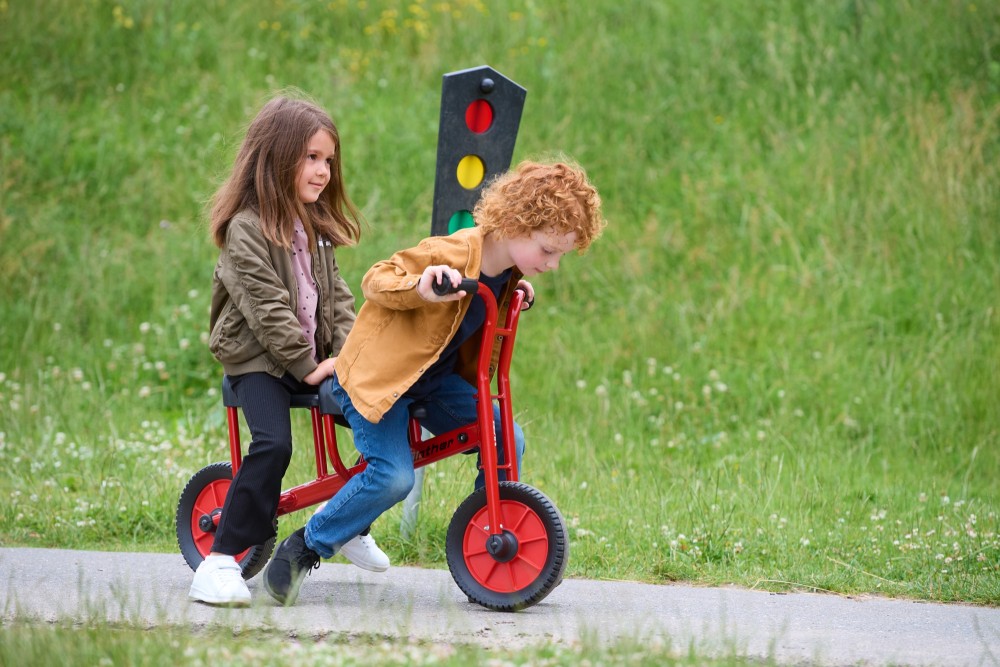 Zwei Kinder auf dem Winther Viking Laufrad Tandem BikeRunner neben einer Spielampel