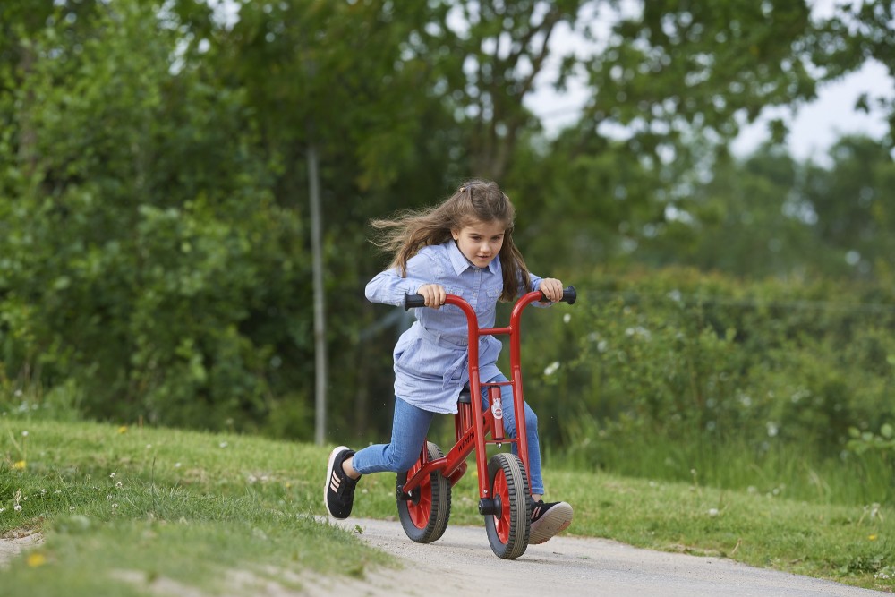 Mädchen fährt das Winther Viking Lernfahrrad auf einem Parkweg