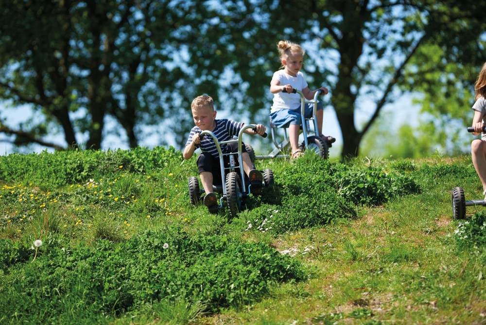 Kinder fahren mit dem Winther Viking OFF-ROAD Dreirad groß über eine Wiese