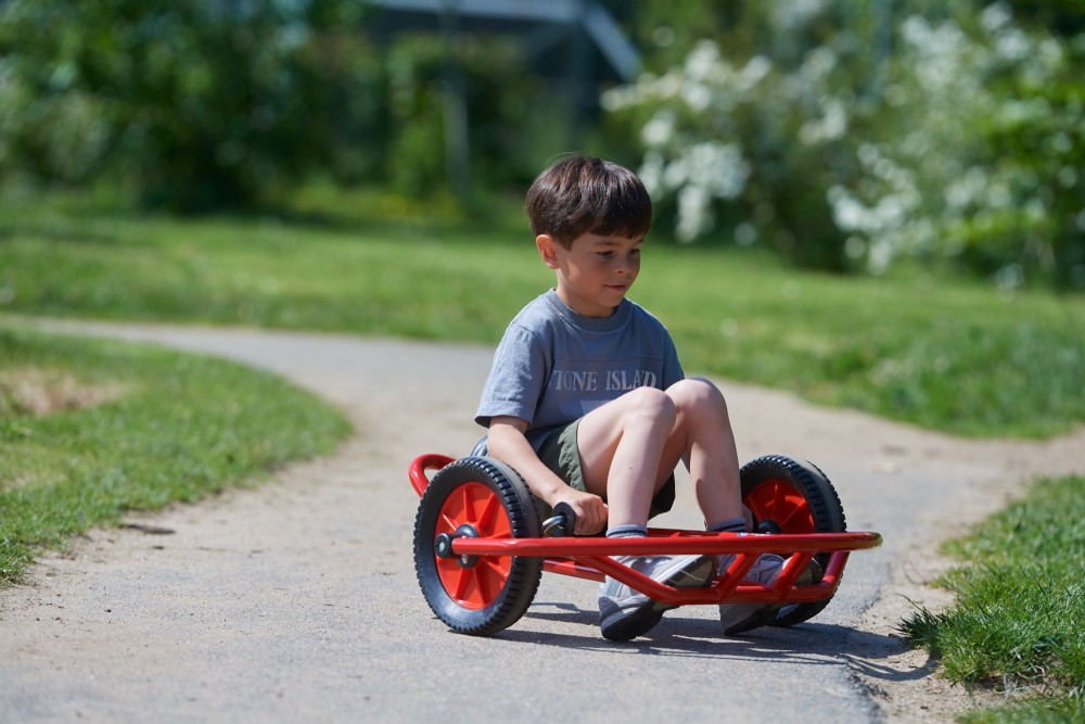 Junge fährt das Winther Viking Swingcart klein auf einem Parkweg